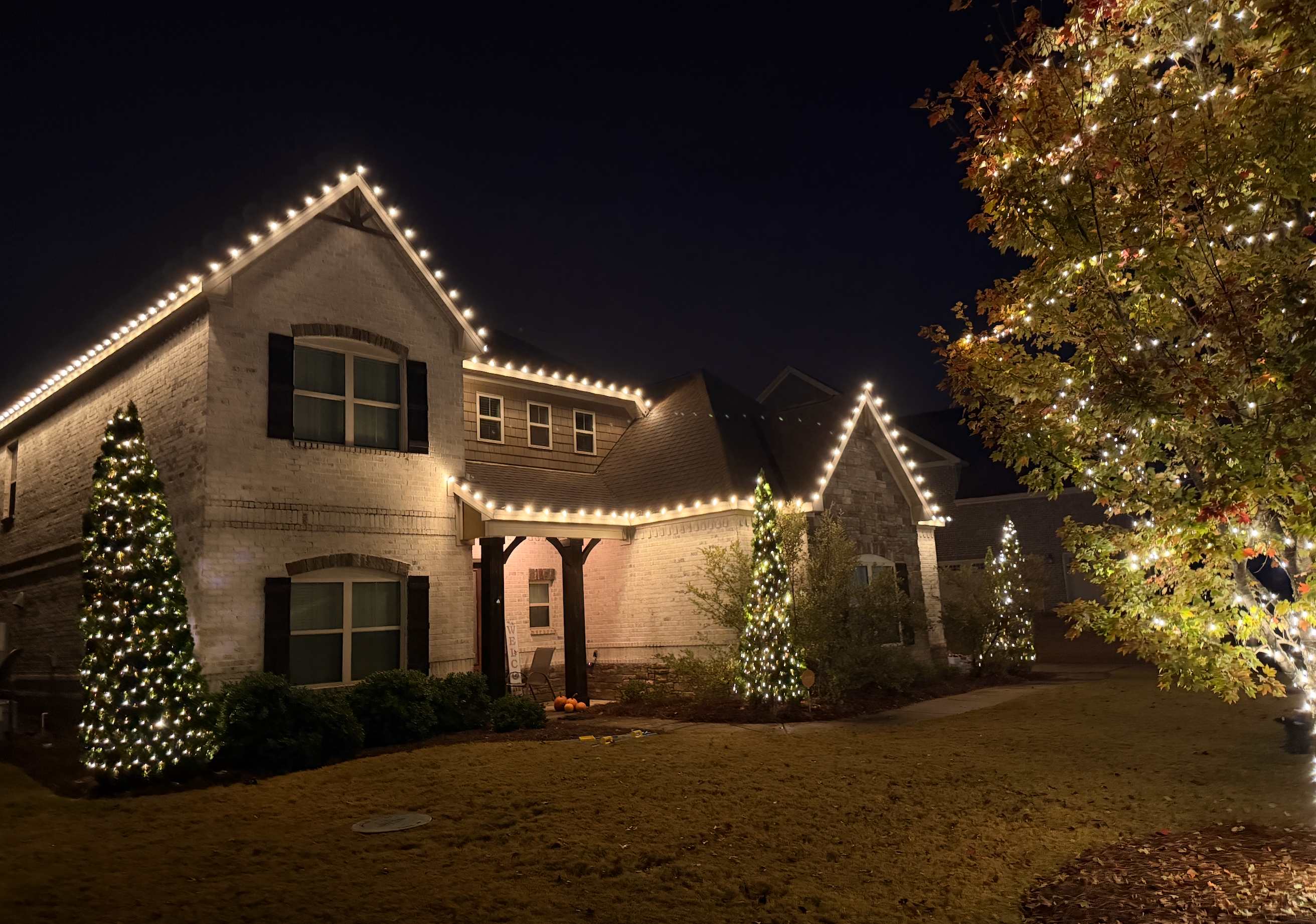 Brick home with Christmas lights and decorated trees